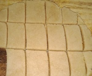   आटे की मोटी रोटी को छोटे-छोटे चकोर टुकड़ों में काटें